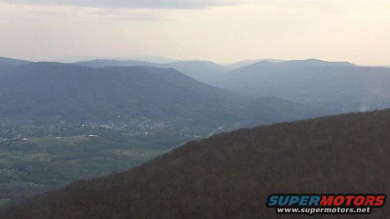 Mountain landscape with distant town and Supermotors logo