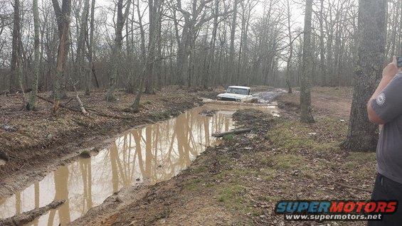 White 1979 Ford Bronco navigating a muddy forest trail