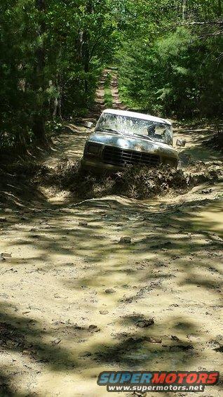 old SUV stuck in deep mud on a wooded trail