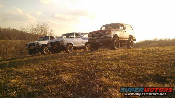 three SUVs parked on a grassy hill at sunset