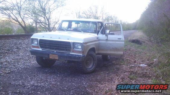 1979 Ford Bronco with open door, parked by railroad tracks
