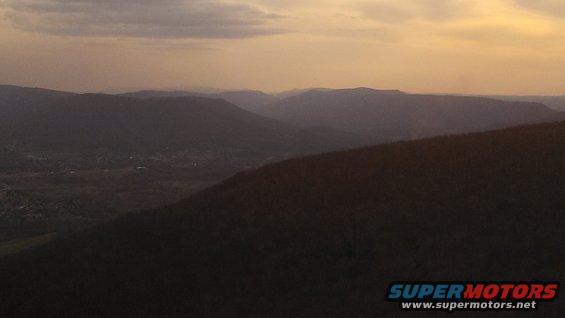 mountain range with valley below at sunset, supermotors.net logo in corner