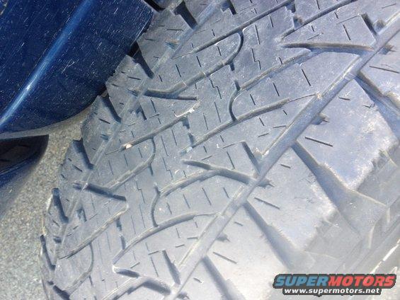 Close-up of a tire tread pattern with blue vehicle paint visible on the left
