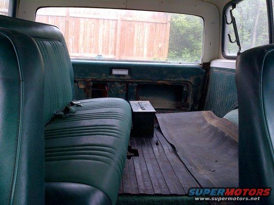 1978 Ford Bronco interior showing green vinyl rear bench seat, wooden floor, and metal toolbox