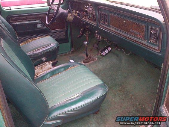 Interior of a green vehicle with worn seats, dashboard, and floor. A "RANGER XLT" badge is visible on the dash