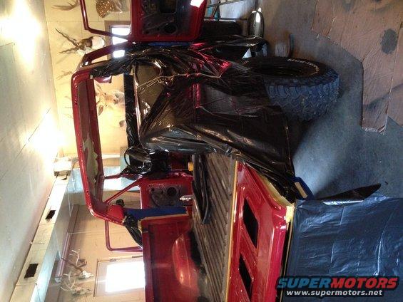 Red SUV with black plastic covering, seen from a 3/4 front angle, indoors
