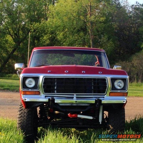 Red Ford truck with chrome grille and headlights, lifted suspension, off-road tires