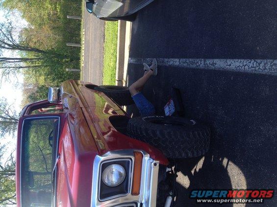 1978 Ford Bronco with person underneath working on the front wheel