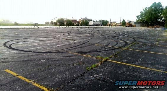Empty parking lot with numerous tire marks from donuts and drifting