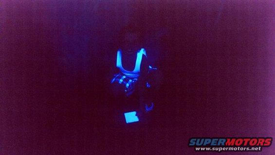 Car interior lit by blacklight, showing glowing blue accents on seats and dashboard