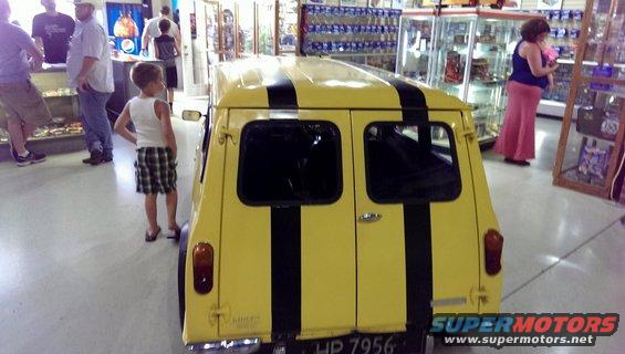 Rear view of a yellow van with two black racing stripes, parked indoors