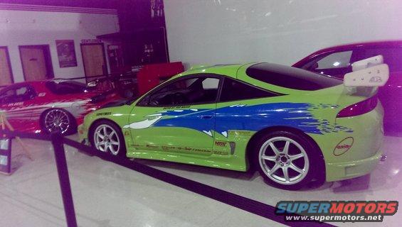 Lime green sports car with blue stripes and a large rear spoiler, parked next to a red car