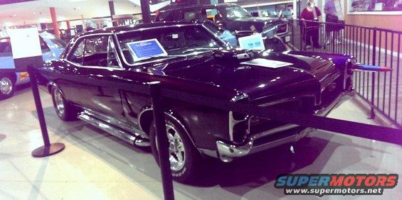 Black 1966 Pontiac GTO coupe with chrome side pipes and aftermarket wheels