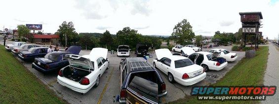 Several white Mercury Grand Marquis sedans parked in a lot with hoods and trunks open