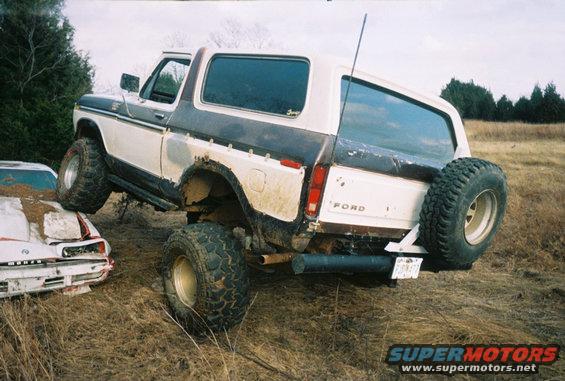 1978 Ford Bronco rear view with spare tire, driving over another vehicle
