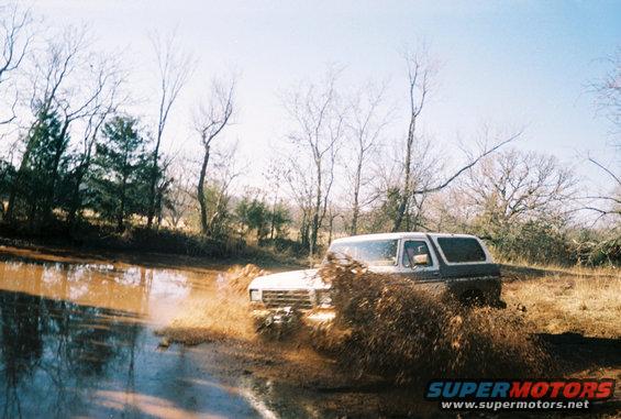 1978 Ford Bronco splashing through a muddy puddle off-road