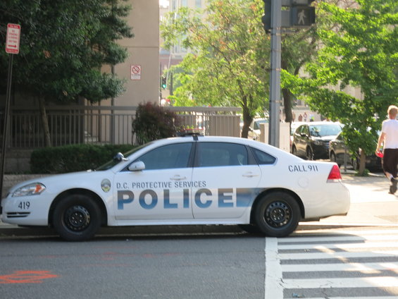 White police car with D.C. Protective Services text and "CALL 911" on the rear quarter panel