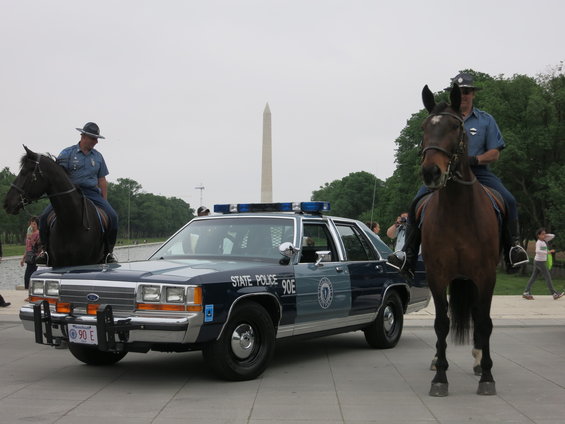 Dark blue and light blue 1991 Ford Crown Victoria police car, front view, with two mounted police officers on horses