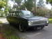1962 Ford Falcon - A matte black station wagon sits parked on a residential street, showing off its distinctive grille and whitewall tires.