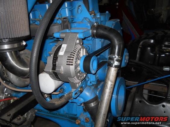 Close-up of an engine's alternator and belt system, with blue engine block visible