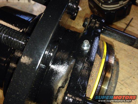 Close-up of a black wheel hub assembly part with a grease fitting and yellow seal