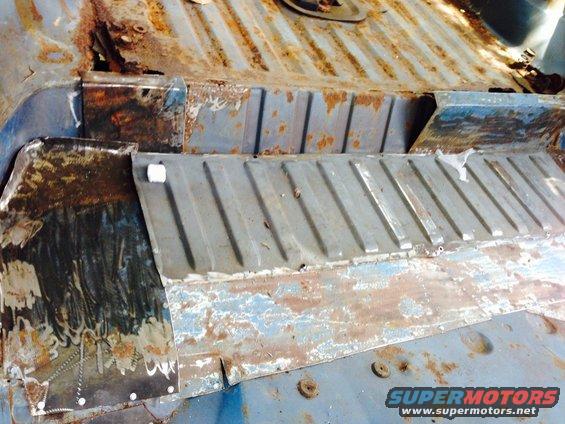 Rusted interior floor pan with visible metal repair patches and surface rust