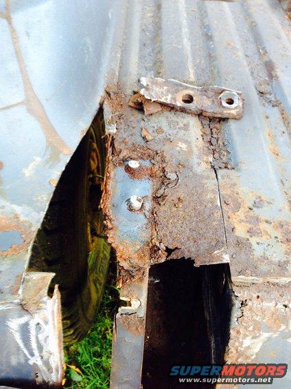 Heavily rusted vehicle frame and wheel well with visible tire