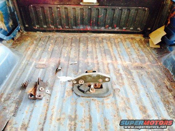 rusted truck bed floor with tie-down anchor and some loose hardware