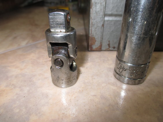 Metal universal joint and socket wrench on a tiled surface