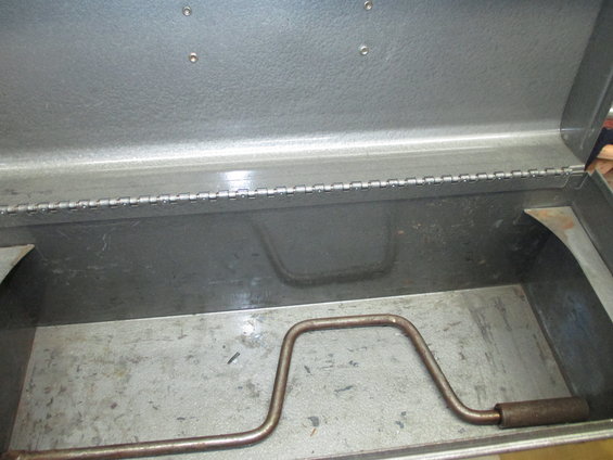 Metal toolbox interior with a rusty crank handle and hinges