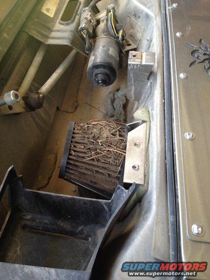 Clogged air filter filled with twigs and debris, with a motor and wiring visible above