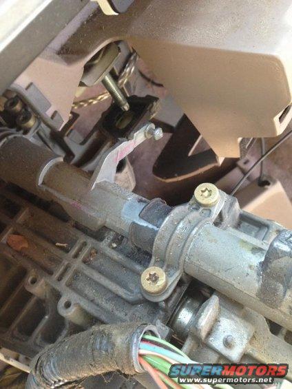 Steering column mechanism with exposed wires and metal parts. A pink sticker is visible