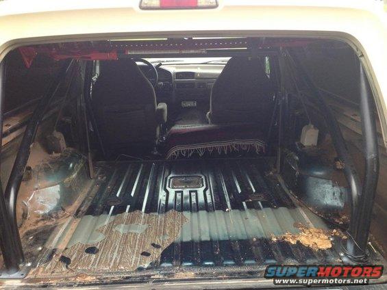 1994 Ford Bronco interior showing roll cage, front seats, and cargo area with dirt
