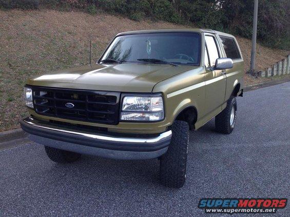 Olive green Ford Bronco with chrome bumper and side stripe
