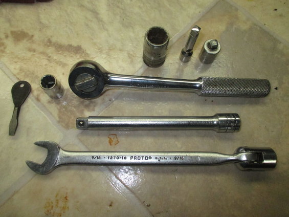Ratchet, socket extension, combination wrench, and sockets on a floor