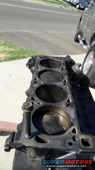 Engine block on a stand, next to a truck wheel and tire