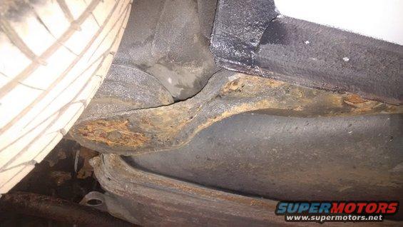 close-up of rusty frame and tire on vehicle undercarriage