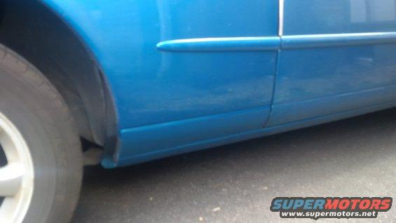 Blue car side panel, door seam, and part of the front wheel well