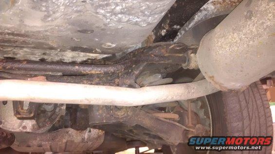 Undercarriage of a vehicle showing rust and exhaust system components