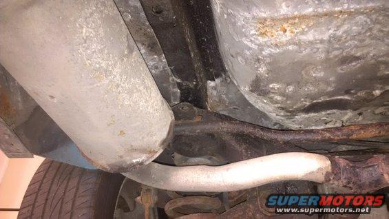 Undercarriage view showing exhaust pipes, suspension, and tire