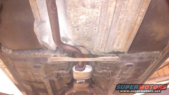 Undercarriage of a car showing rust and an exhaust pipe with a muffler