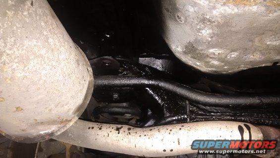 Undercarriage view of exhaust pipe and suspension components with black undercoating