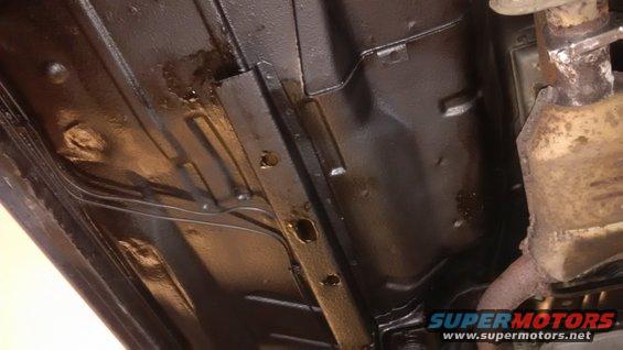 Underside of vehicle showing rust repair and undercoating. Supermotors.net logo visible