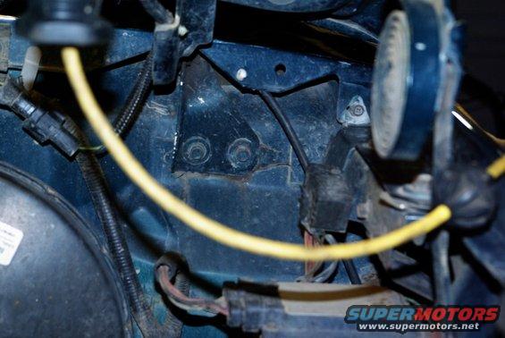 Close-up of dark blue engine bay with yellow wire, black hoses, and electrical connectors