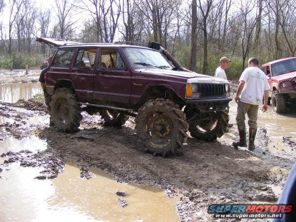 Maroon Jeep Cherokee XJ with oversized tires in mud