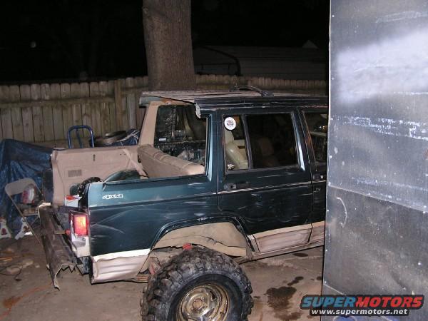 Green Jeep Cherokee XJ with a tan interior, parked next to another vehicle. The rear of the Jeep is visible