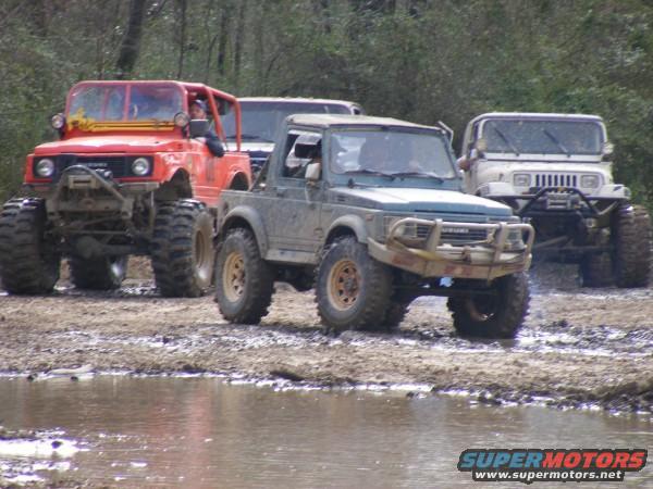 Four modified off-road vehicles in a muddy area
