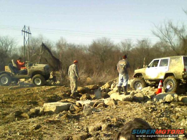 Off-road vehicles navigating a rocky terrain with three people present