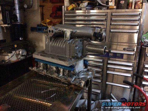 Supercharger unit sitting on top of an engine block, with a toolbox in the background