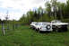 1989 Ford Bronco - Three trucks are parked in a grassy field with a wooden fence and trees.